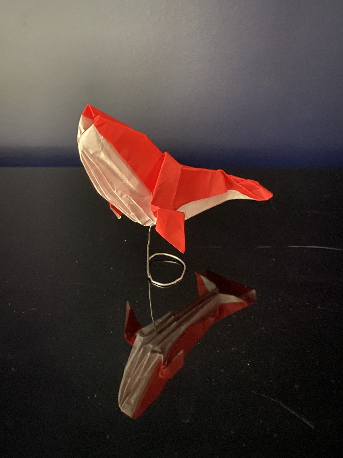 A paper humpback whale on a paper clip stand. 